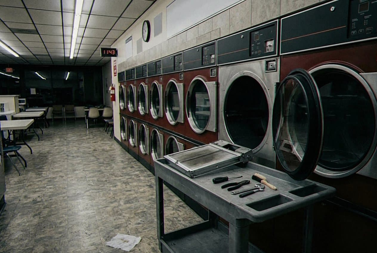Row of commercial dryers in a dim laundromat
